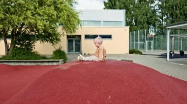 Şehir parkında çocuk parkında koşan neşeli çocuk. Çocuk sokakta oyun parkında oynuyor. Çocuk dışarıda yürüyor. 2 yaşında şık giyinmiş bir çocuk..