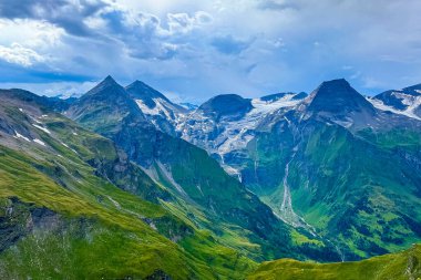 Dönen gökyüzünün altındaki yeşil manzaralar üzerinde sersemletici tepeler, sakin bir yaz gününde Alpler 'deki doğanın güzelliğini yansıtıyor..