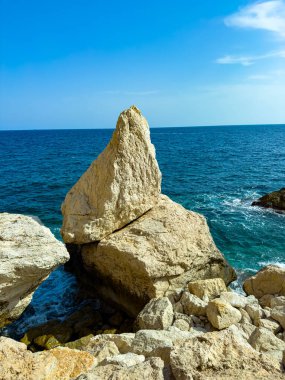 Nefes kesici kireçtaşı kayaları, güneş ışığının dokunduğu dalgaların üzerinde dimdik durur ve berrak bir gökyüzünün altında derin mavi suyla çevrili, doğanın sanatsal güzelliğini yakalar..