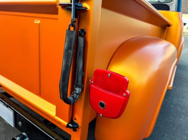 Altın güneş ışığı altında, eski turuncu bir kamyon gururla durur. Parlak arka hatlar ve kırmızı detaylar klasik otomotiv tasarımının cazibesini yakalar, hayranlık uyandırır..