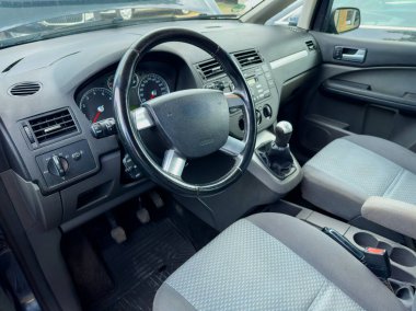 Modern bir aracın içinde, gösterge paneli gerekli kontrollere ve şık bir tasarıma sahiptir. Yumuşak kumaş koltuklar konfor sağlar, bulutsuz gökyüzünün altında hoş bir yolculuk davet eder..