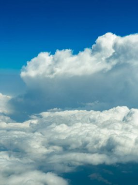 Pofuduk beyaz bulutlar sonsuz kadar uzayıp canlı mavi bir gökyüzünün altında yumuşak bir manzara yaratırlar. Barışçıl atmosfer yüksek irtifada merak ve özgürlük hissi uyandırıyor..