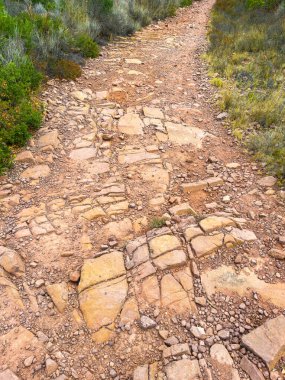 Büyük taşlardan yapılmış engebeli bir yol ve yeşil çalıların ve yabani otların arasında dolanan toprak. Öğleden sonra güneşi, aylakları doğanın güzelliğini keşfetmeye davet ediyor..