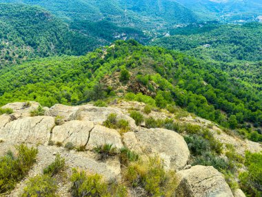 Dağ zirvesinden nefes kesici bir manzara yemyeşil ormanları, engebeli kayaları ve uzak vadileri gösteriyor. Güneş, sakin vahşi doğada parlıyor. Maceraya davetiye çıkarıyor..