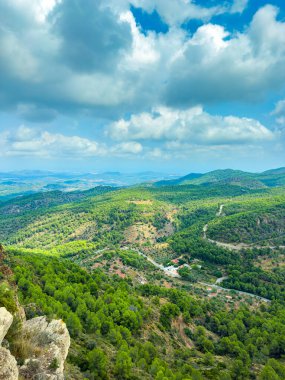Bereketli yeşil tepeler, tüylü beyaz bulutlarla dolu açık mavi bir gökyüzünün altında sakin bir öğleden sonra boyunca doğanın güzelliğini gözler önüne seriyor..