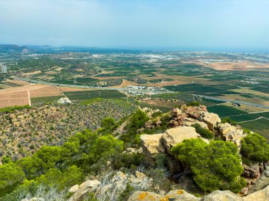 Dağın tepesinden geniş bir manzara, güneşli bir günde mavi bir gökyüzünün altındaki vadi boyunca uzanan yemyeşil üzüm bağlarını ve tarım arazilerini gözler önüne seriyor. Bölge huzurlu ve el değmemiş..