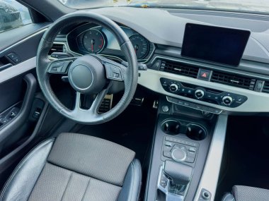 Gösterge paneli, direksiyon simidi ve rahat koltuklara odaklanarak bir arabanın iç tasarımı ve teknolojisini keşfetmek. Sahne, şehir atmosferini ve modern elementleri yakalıyor..