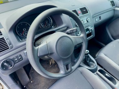 Boş bir arabanın içi, güneşli bir günde huzurlu bir sürüşün basitliğini yansıtan göstergeli gösterge paneli ve göstergeli direksiyonu gösteriyor..