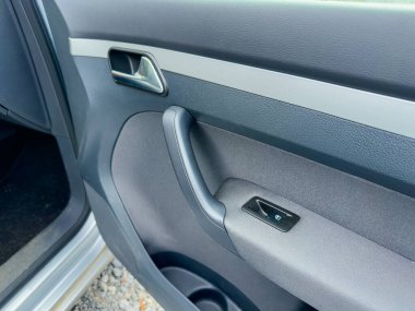 Yakından bakıldığında, parlak gün ışığında konfor ve modern tasarımın bir karışımını sergileyen şık bir araba kapısı kolu ve iç hatları ön plana çıkıyor..