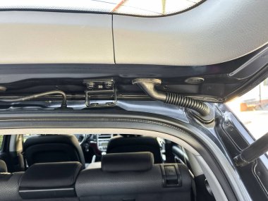 Arabanın iç mekânının yakın görüntüsü, sunroof mekanizmasına ve arka koltuğun parlak güneş ışığı altındaki parlak tasarımına odaklanıyor..