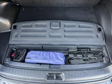 Bir aracın bagajında, düzenli bir depolama bölmesi araç gereçler ve kişisel eşyalar da dahil olmak üzere seyahat ve kolaylık için organize bir yaklaşımı vurgulayan çeşitli malzemeler barındırır..