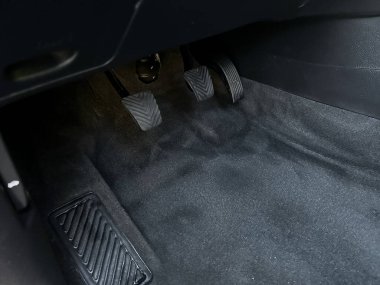 Bu sahne, tertemiz zemini ve temiz pedalları olan bir arabanın içini gösteriyor. Dikkatli bakımı yansıtıyor. Bir düzen ve temizlik duygusu mevcut, tipik araç bakımı..