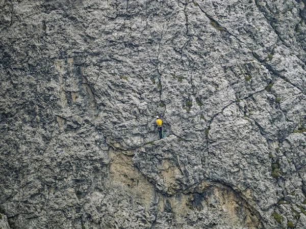 穿着黄色衬衫在山墙上孤独地攀爬的人 — 图库照片