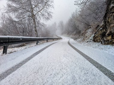 Snow on a road in winter season in the italian prealps clipart