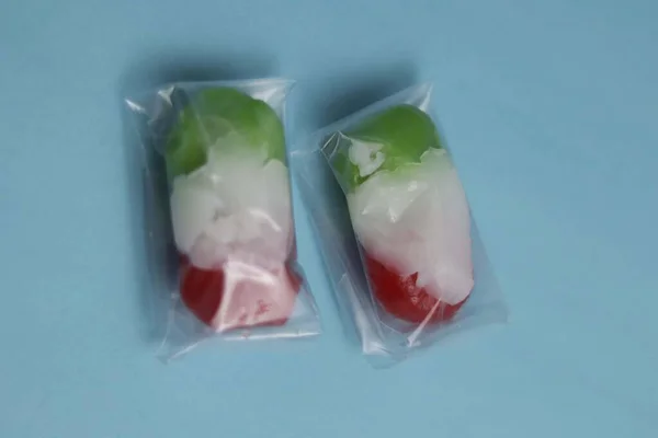 stock image red and green market snacks filled with sweet grated coconut. market snacks on a blue background