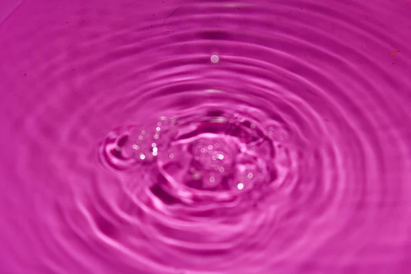 Pembe arka planda su damlası