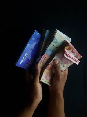 Milyonlarca rupiahı olan siyah bir arka planı olan kişi.