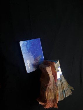 Güney Lampung, 03 Mart 2023; BRI Tasarruf Defteri ve Milyonlarca Rupiah siyah arka planda