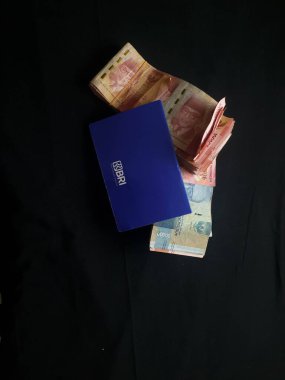 Güney Lampung, 03 Mart 2023; BRI Tasarruf Defteri ve Milyonlarca Rupiah siyah arka planda