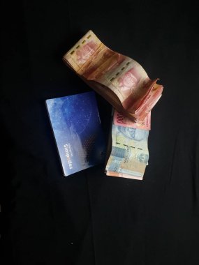 Güney Lampung, 03 Mart 2023; BRI Tasarruf Defteri ve Milyonlarca Rupiah siyah arka planda