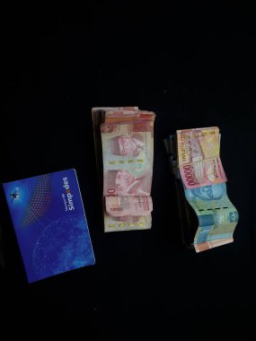 Güney Lampung, 03 Mart 2023; BRI Tasarruf Defteri ve Milyonlarca Rupiah siyah arka planda