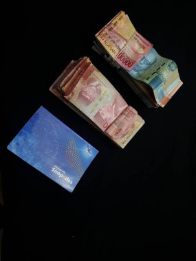 Güney Lampung, 03 Mart 2023; BRI Tasarruf Defteri ve Milyonlarca Rupiah siyah arka planda