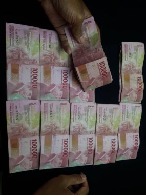 Milyonlarca Rupiah 'ın siyah arka planda olduğu bir el.