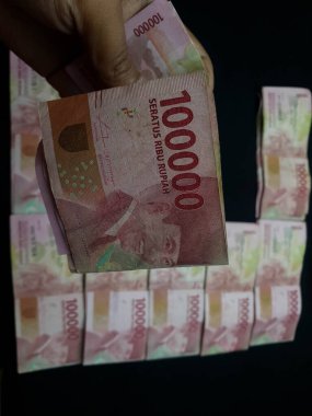 Milyonlarca Rupiah 'ın siyah arka planda olduğu bir el.