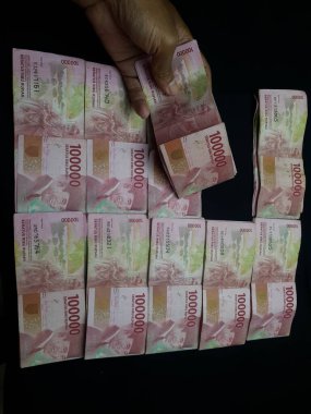 Milyonlarca Rupiah 'ın siyah arka planda olduğu bir el.