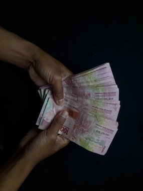 Milyonlarca Rupiah 'ın eli siyah bir arkaplanda.
