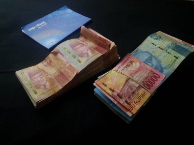 Güney Lampung, 03 Mart 2023; BRI Tasarruf Defteri ve Milyonlarca Rupiah siyah arka planda