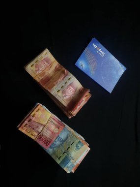 Güney Lampung, 03 Mart 2023; BRI Tasarruf Defteri ve Milyonlarca Rupiah siyah arka planda