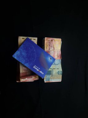 Güney Lampung, 03 Mart 2023; BRI Tasarruf Defteri ve Milyonlarca Rupiah siyah arka planda