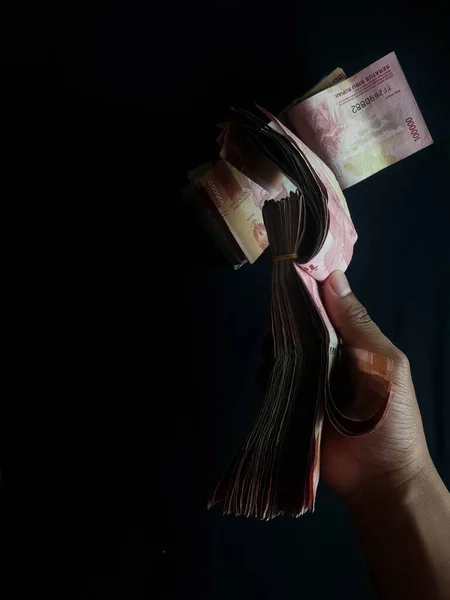 一只男性的手拿着几百万印尼盾的黑色背景货币 — 图库照片