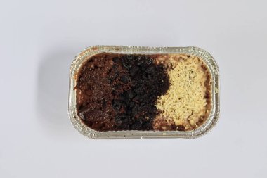 Erimiş brovniler üzerine peynir serpiştirilmiş ve lezzetli çikolatalar turuncu bir tepside beyaz arka planda.