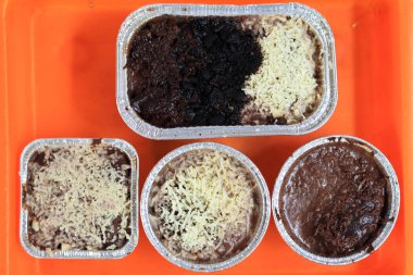 Erimiş brovniler üzerine peynir serpiştirilmiş ve lezzetli çikolatalar turuncu bir tepside beyaz arka planda.