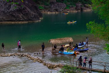 Yogyakarta, Endonezya - 3 Ağustos 2023: Suyun çok temiz ve yeşil olduğu nehir manzarası. İnsanlar Kedung Jati Parang, Selopamioro 'da kano yapıyor..
