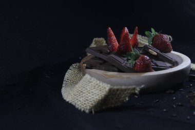 Siyah arka planda çilekli çikolatalar.