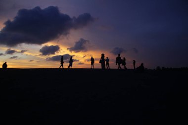 Sahildeki insanların silueti.