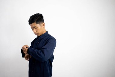 Stüdyoda mavi gömlekli Asyalı adam var..