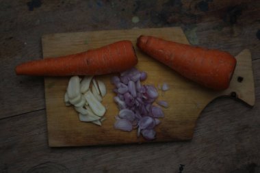 Tahtada taze sarımsak ve havuç dilimlenmiş.