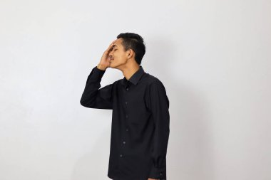 Beyaz bir arka planda endişeli yüz ifadesi olan Endonezyalı bir adam.