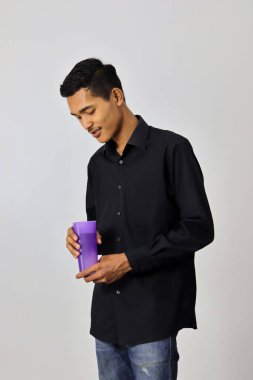 Gri stüdyo arka planında su şişesi olan Asyalı bir adam..