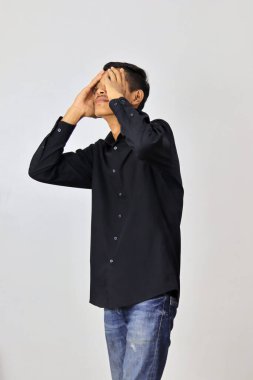 Beyaz bir arka planda endişeli yüz ifadesi olan Endonezyalı bir adam.