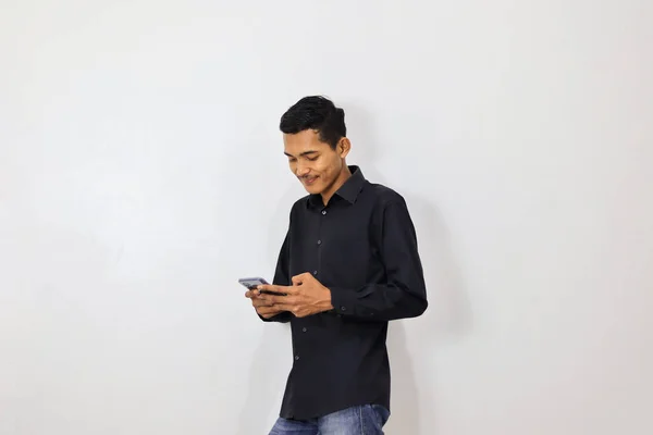 身穿海军蓝衬衫的亚洲年轻人 背景为白色 使用智能手机 — 图库照片
