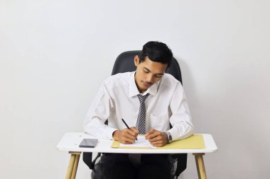 Ofiste çalışan Asyalı genç adam, masada oturuyor. 