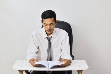 Ofiste çalışan Asyalı genç adam, masada oturuyor. 