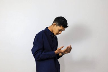 Genç adam gündelik kıyafetler giyip dua ediyor. 