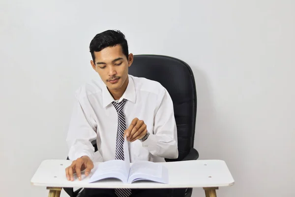 Asian young man working in office, sitting on desk