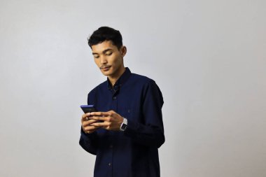 Genç yakışıklı Asyalı işadamı, izole edilmiş arka planda duran akıllı telefonu kullanıyor.